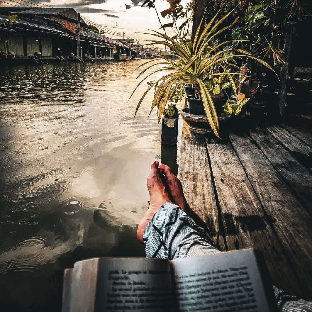pause lecture devant les klong d'amphawa en thailande livre ouvert et pieds