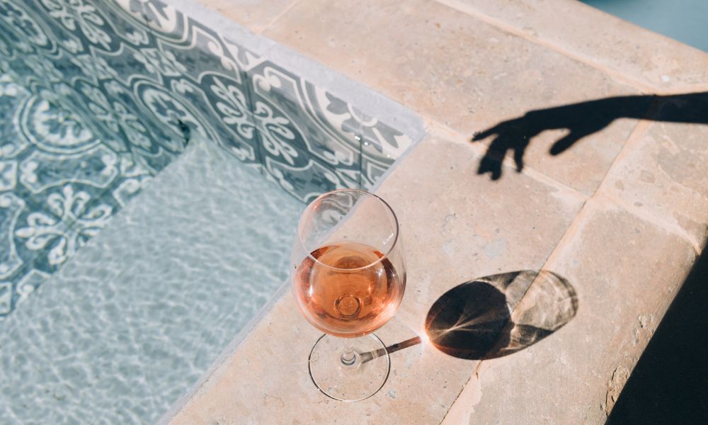 verre de rosé posé au bord d'une piscine
