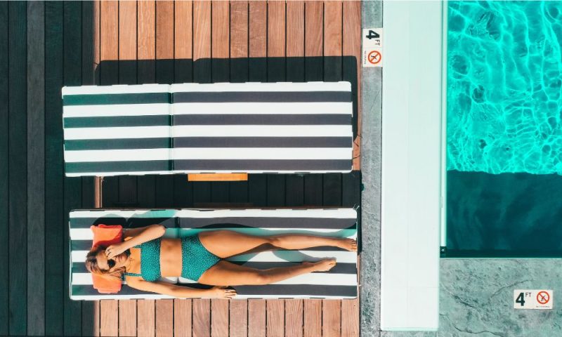 femme allongée sur un transat au bord d'une piscine