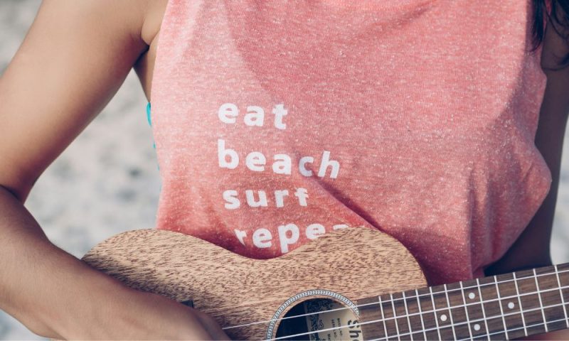 tee shirt rose de femme tenant une guitare aricle bienfaits du voyage