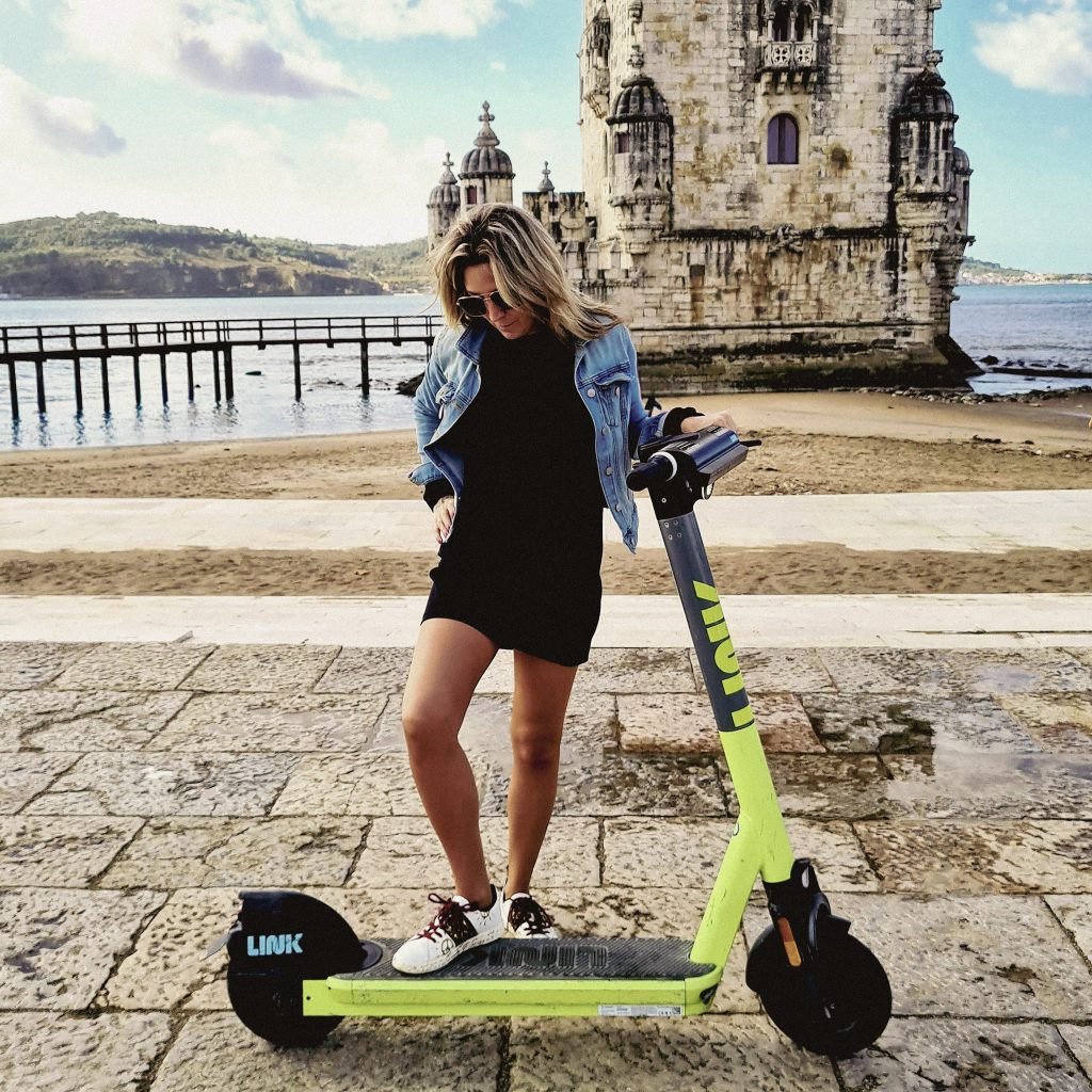 femme en trotinette devant la tour de belem a lisbonne
