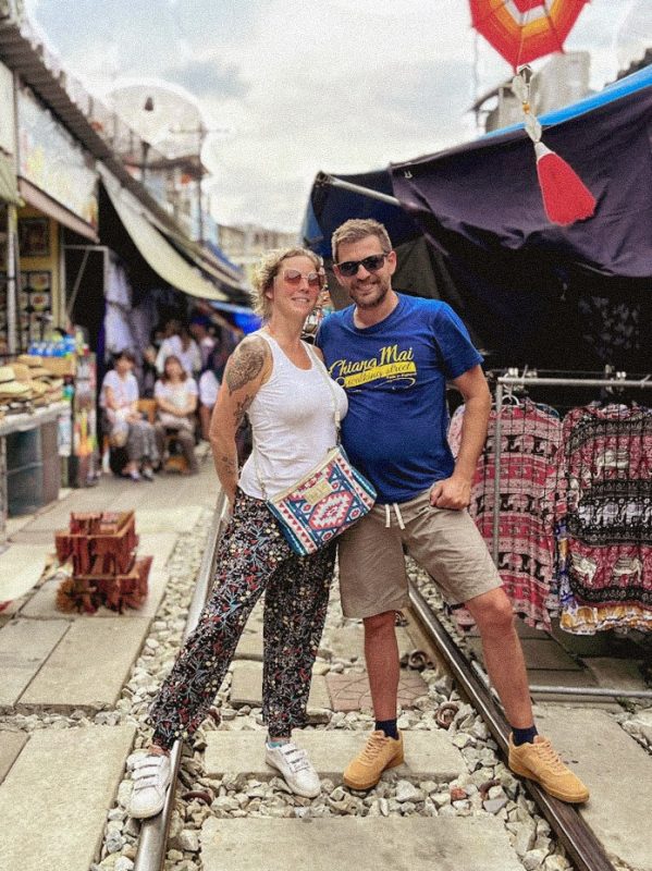 couple sur les rails du train au marché de mae klong en thailande