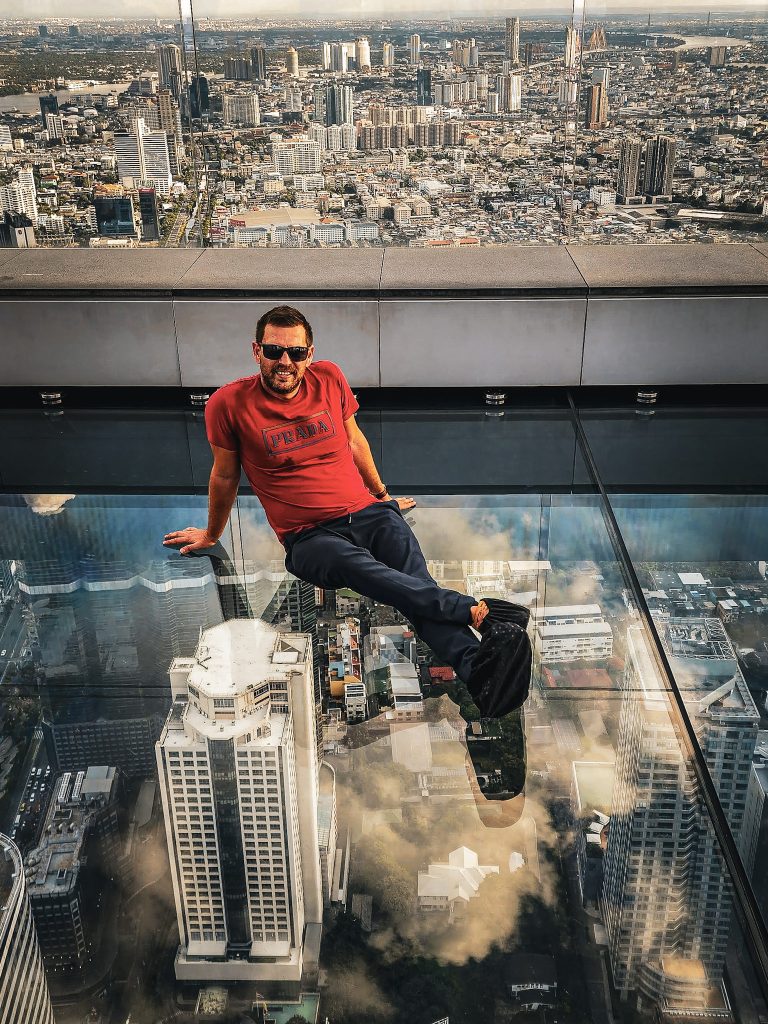homme assis sur le sol transparent de la mahanakhon tower a bangkok