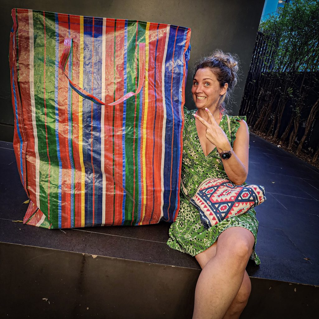 Lucie assise à côté d'un sac cabas géant après une journée de shopping à Bangkok.