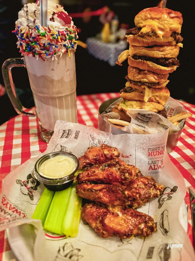 ailes de poulet milkshake et burger sur une nappe a carreau rouge et blanc