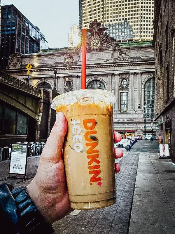 main tenant un café latte dunkin donuts devant gran central terminal 