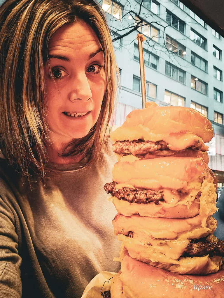 femme degustant un burger de plusieurs etages
