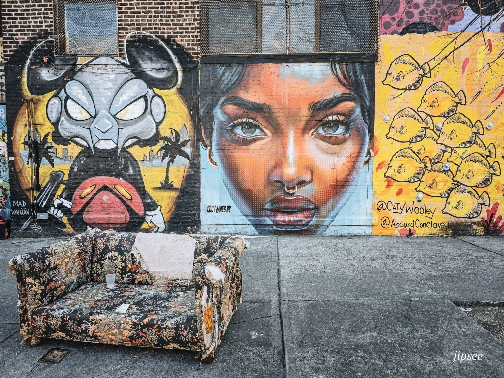 canapé dans la rue devant un mur de street art