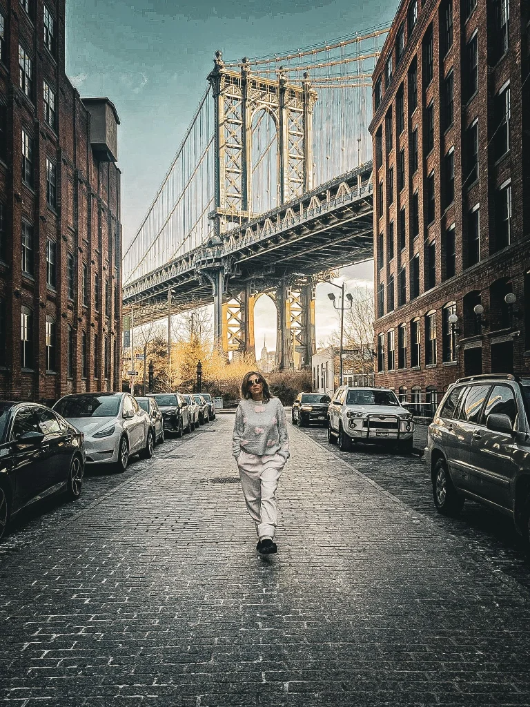 femme marchant dans une rue devant le brooklyn bridge