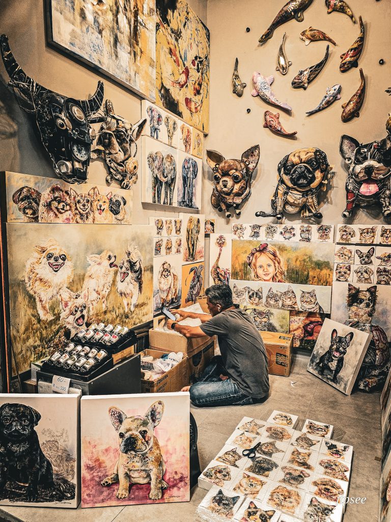 artiste en plein travail au milieu de ses peintures au marche de chatuchak