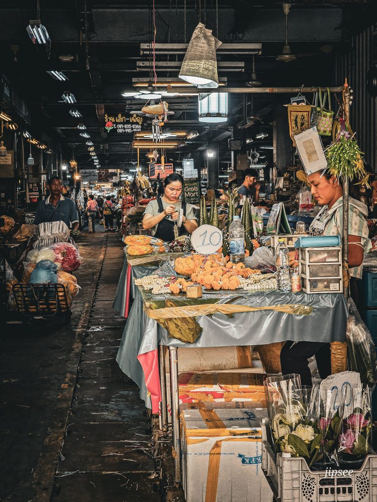 vendeuse preparant des couronnes de fleurs dans un marché de bangkok