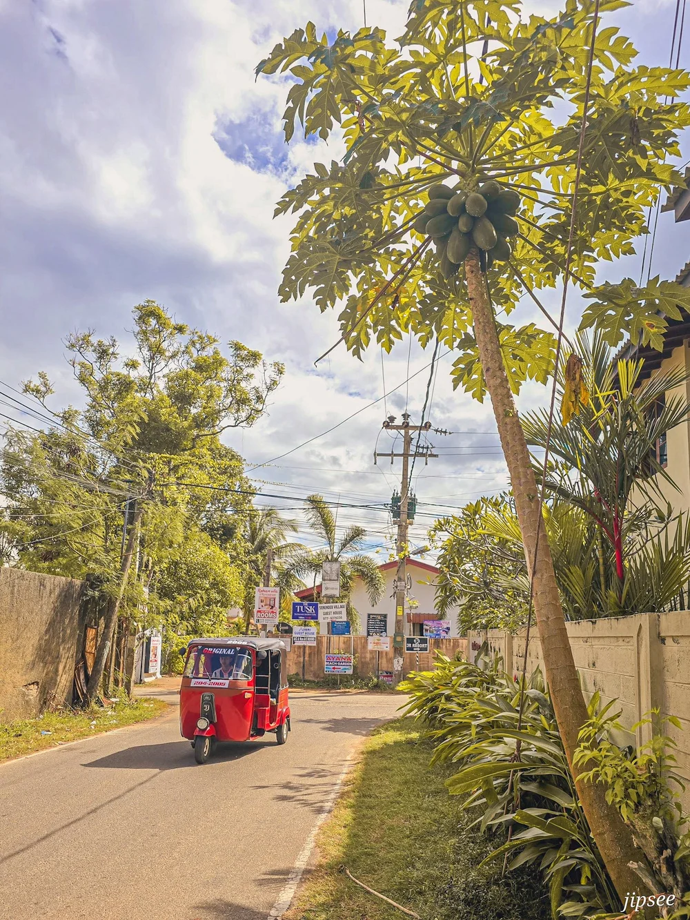 tuk tuk rouge remontant une rue d'un quartier residentiel de negombo