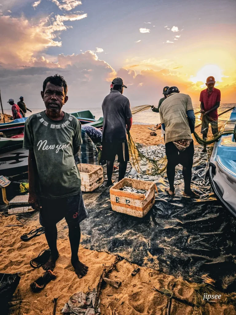 pecheurs triant les poissons dans un filet a cote de leur bateau