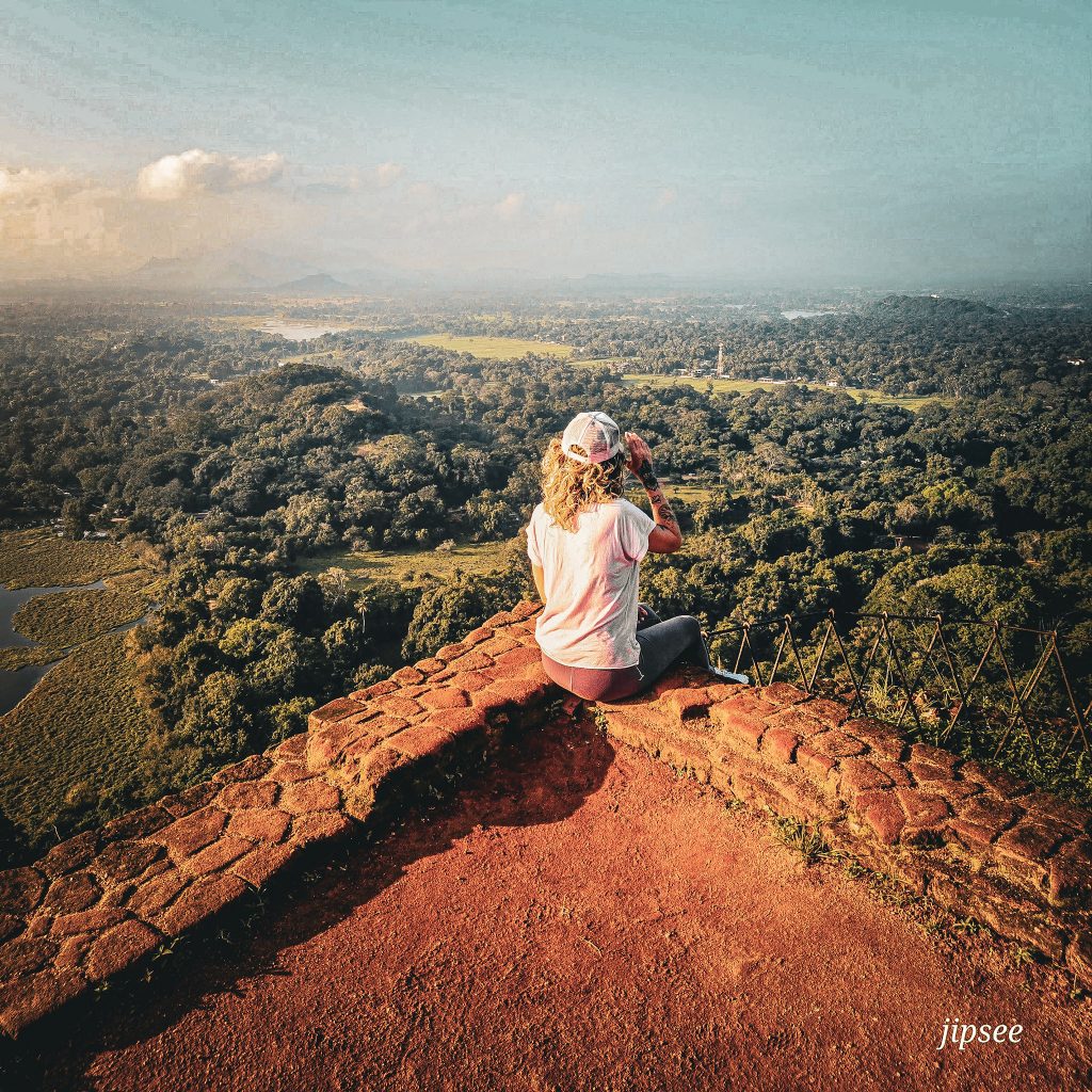femme de dos assisie au sommet du rocher du lion a sigiriya au sri lanka