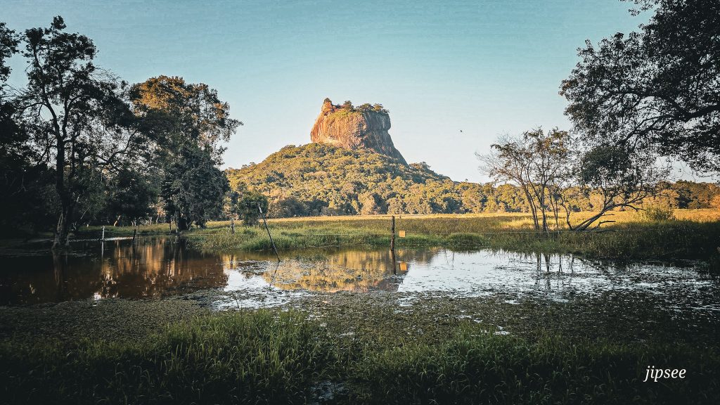 vue du rocher du lion au loin face a un lac a sigiriya au sri lanka