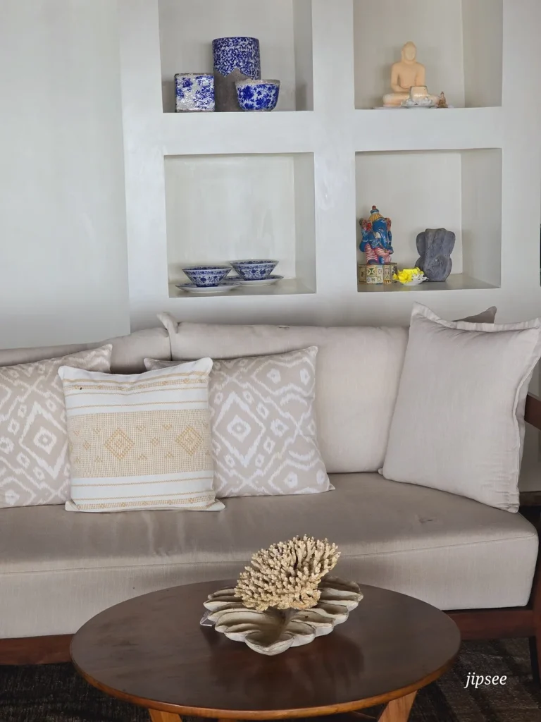 canapé beige etagere avec bibelots decoratifs derriere