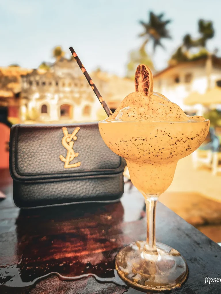 sac a main et cocktail avec paille posé sur une table noire