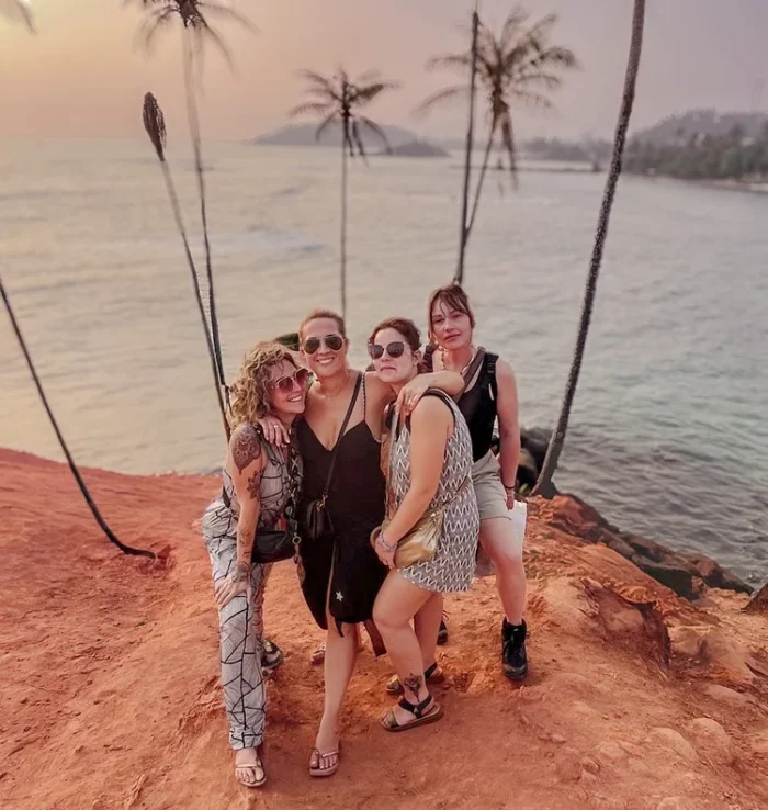 quatre filles prenant la pose devant des palmiers en bord de plage