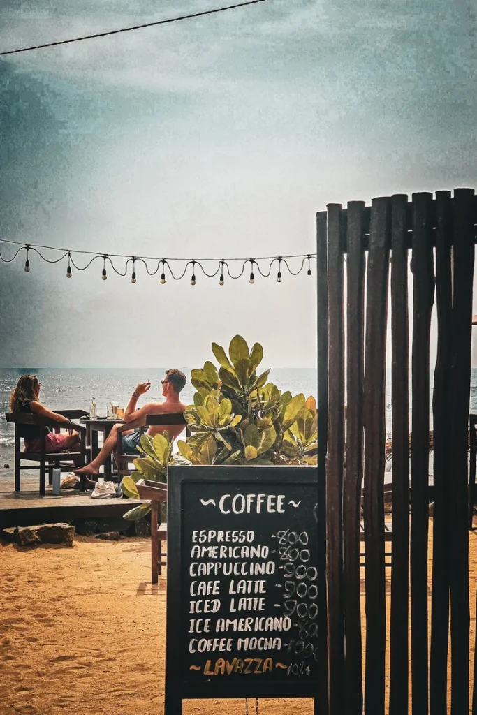 panneau menu de café et couple attablé sur une terrasse