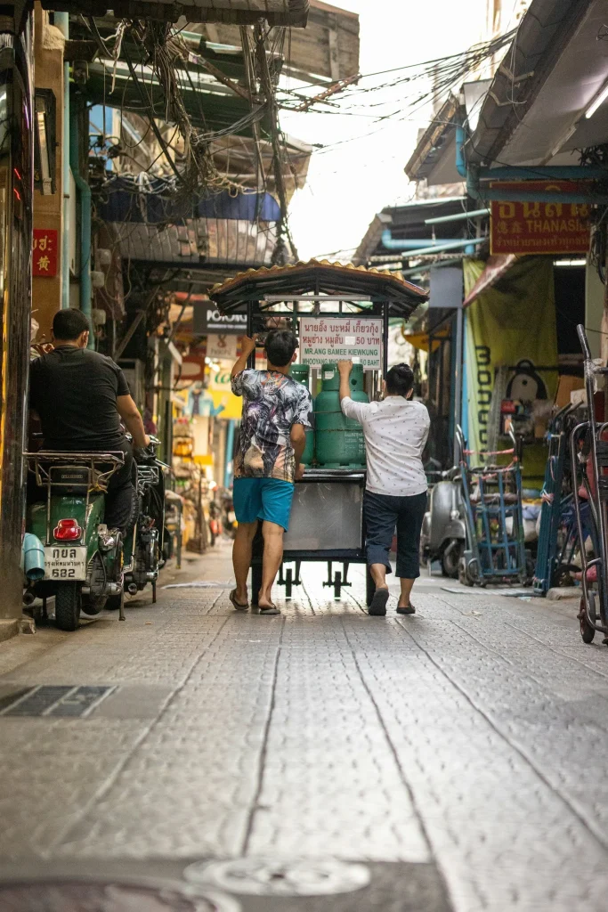 deux hommes poussant une cariole dans une rue de chinatown a bangkok