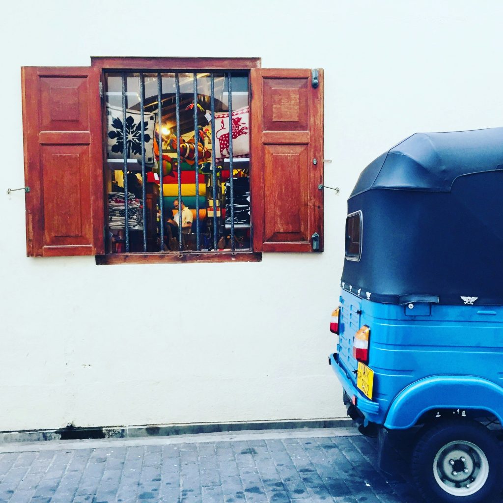 tuk tuk bleu devant une fenetre et un mur blanc dans le centre historique de galle au sri lanka