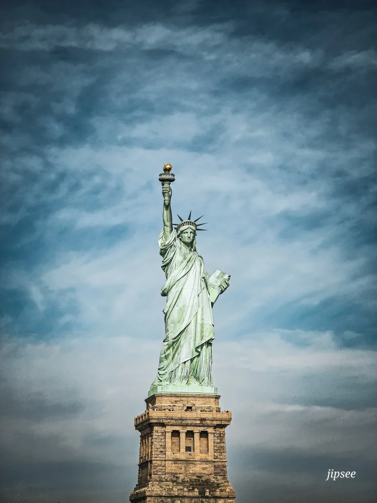 la statue de la liberté devant un ciel legerement nuageux