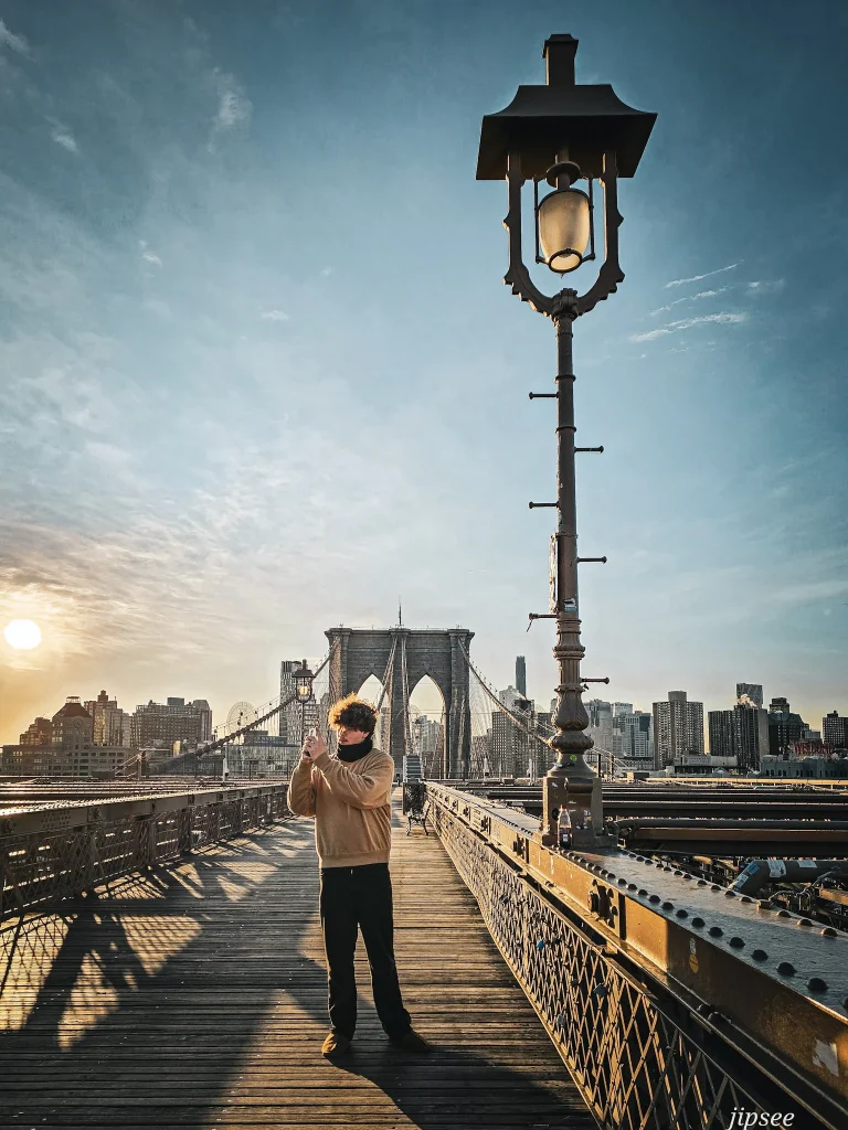 homme prenant une photo avec son telephone sur le pont de brooklyn