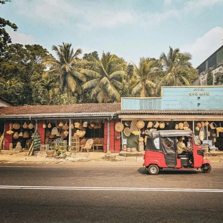 tuk tuk sur une route devant un alignement de boutiques de vanneries au sri lanka
