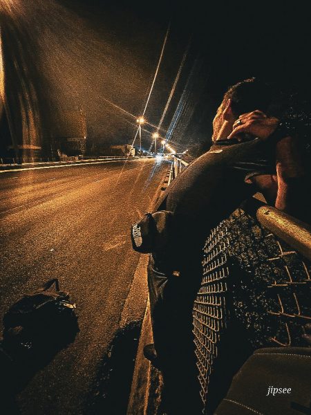 homme sur un grillage au bord d'une autoroute de bangkok la nuit