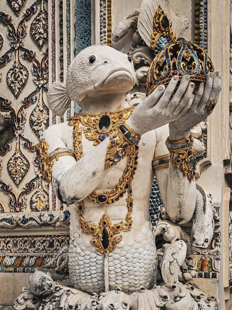 sculpture de personnage mi poisson mi homme tenant des bijoux au temple wat pariwat bangkok