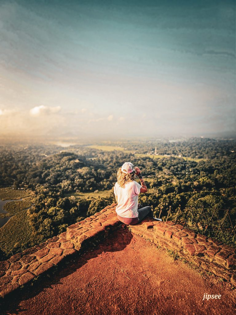 femme de dos avec une casquette rose assise au sommet du rocher du lion a sigiriya au sri lanka