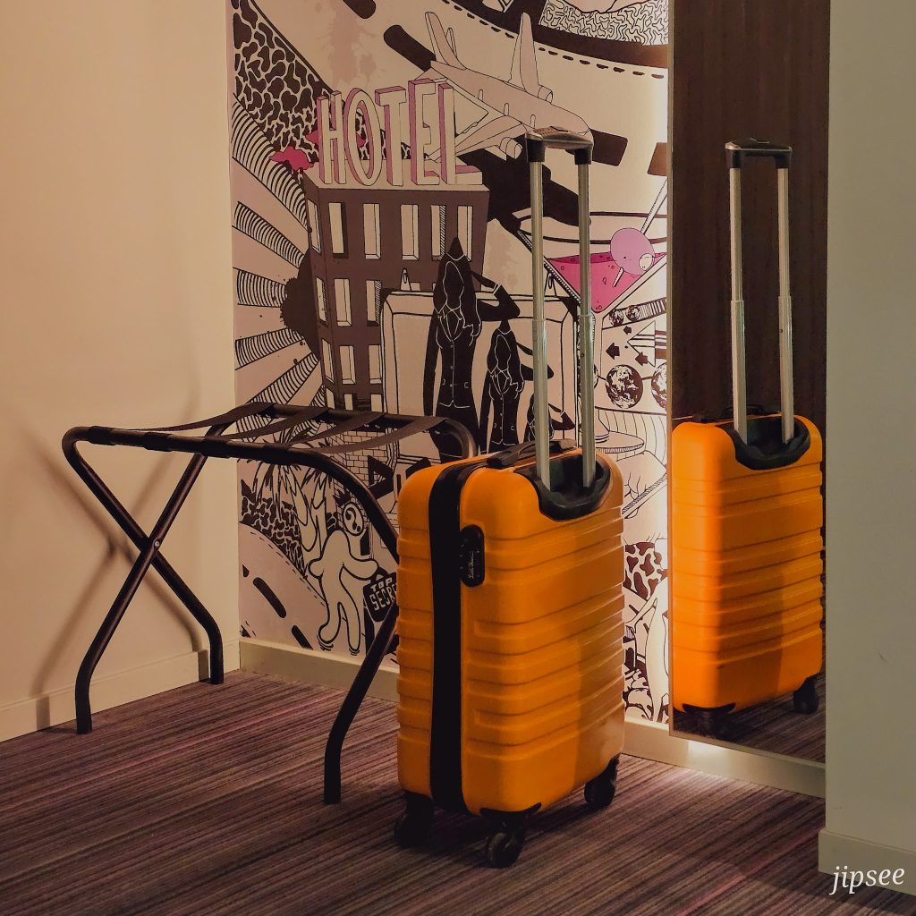 valise posée a l'entree de la chambre du moxy hotel a paris devant un miroir