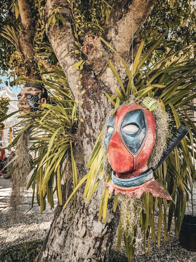 masque de spiderman decale pendu dans un arbre du temple blanc en thailande