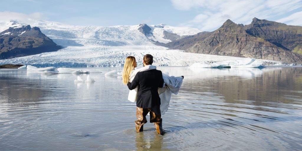 homme tenant une femme dans ses bras devant une montagne enneigée