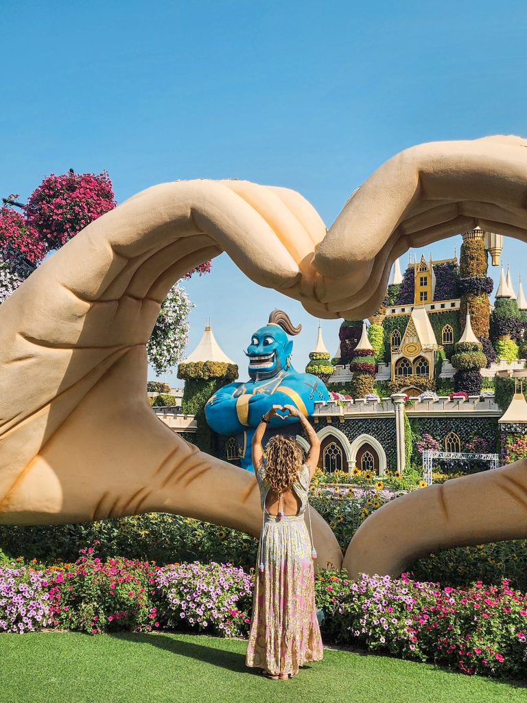 femme de dos posant devant des mains en coeur et un genie bleu au dubai miradcle garden