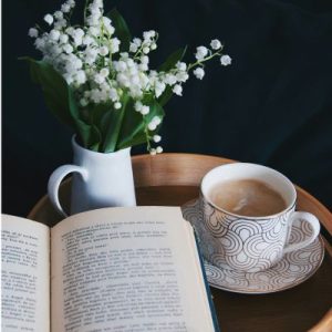 tasse de cafe bouquet de muguet et livre ouvert sur une table