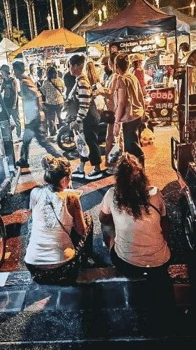 deux femme assises sur un trottoir entre deux tuk tuk