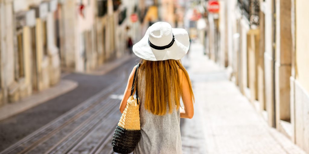femme cheveux long se promenant dans une ville avec un chapeau sur la tete