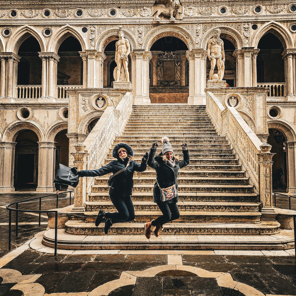 deux femmes sautant devant l'escalier du palais des doges a venise