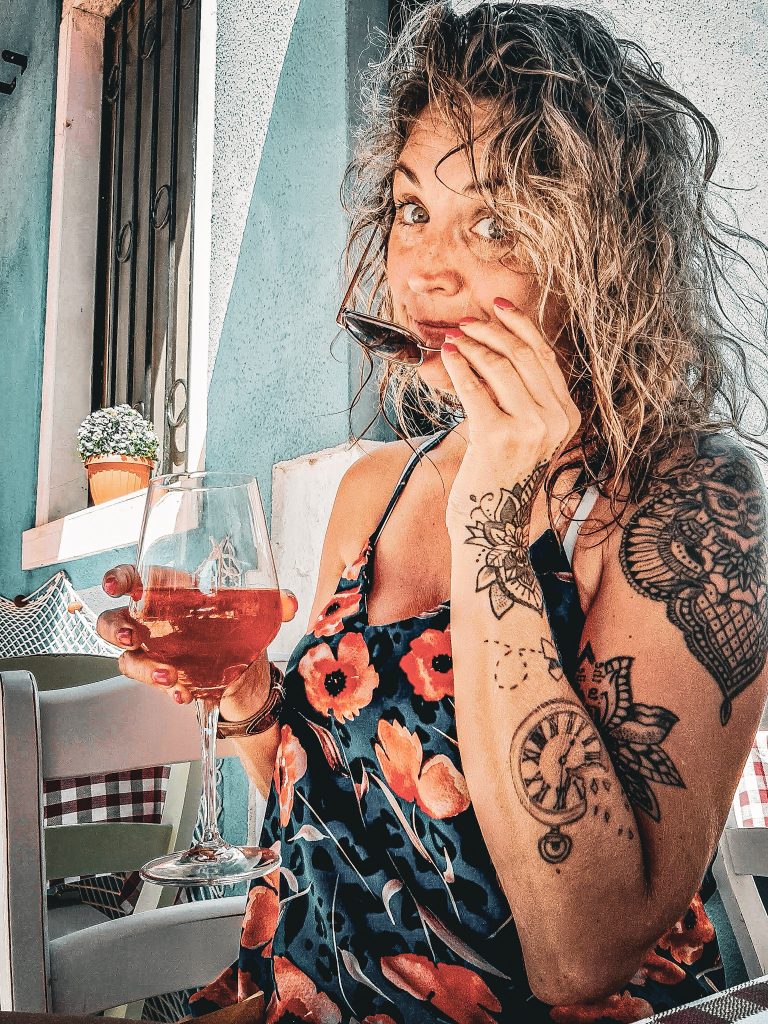 femme tenant un spritz a la main sur une terrasse de burano