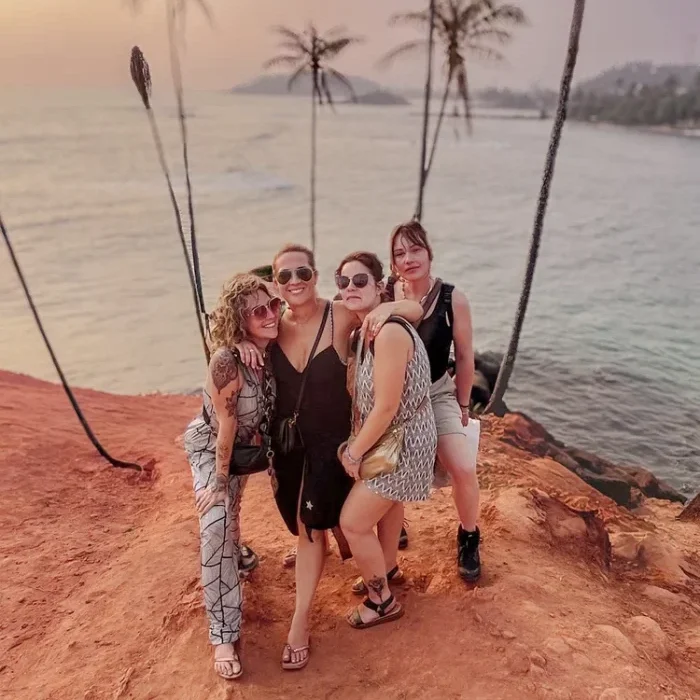 quatre filles prenant la pose devant des palmiers en bord de plage