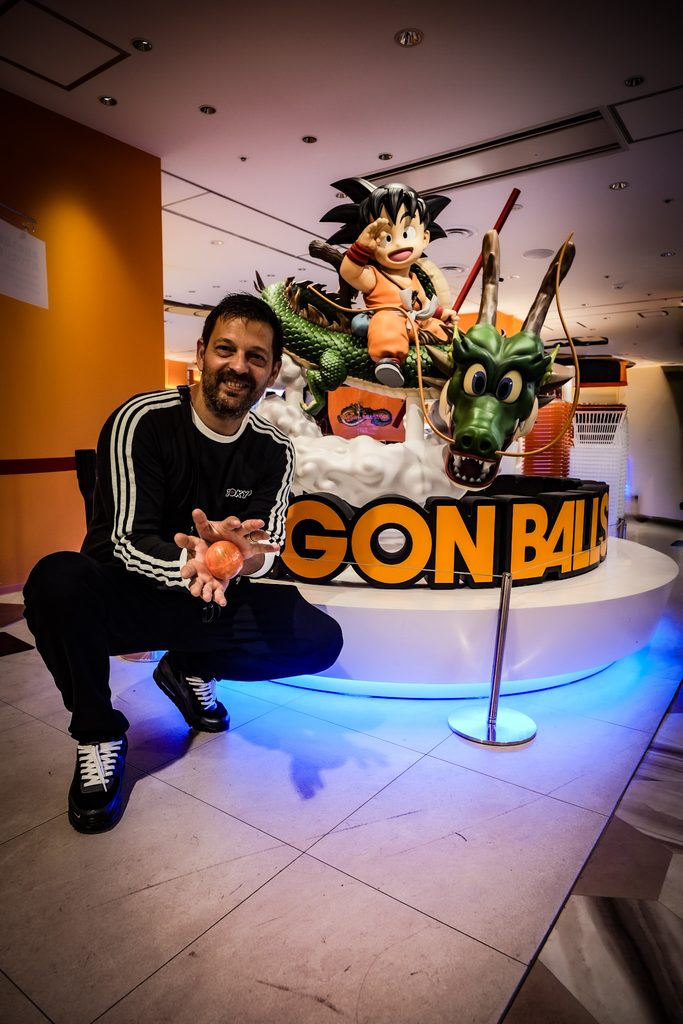 homme devant une reproduction de dragon ball dans une boutique de tokyo
