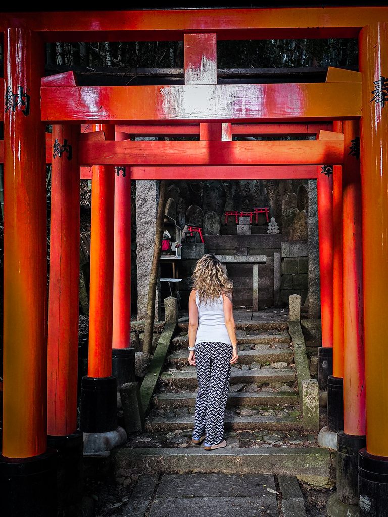 femme de dos devant un torii rouge de fushimi inari a kyoto