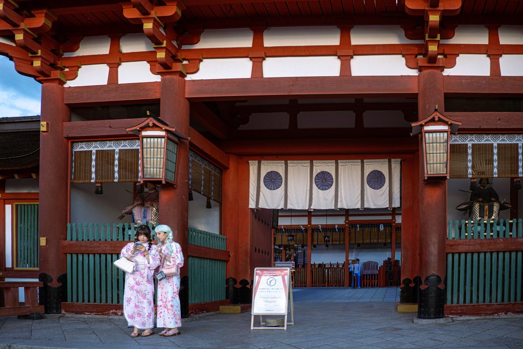 deux jeunes filles en tenue traditionnelle devant un temple de kyoto au japon
