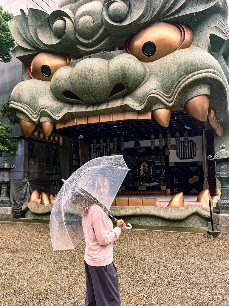 femme avec un parapluie devant la tete de dragon du sanctuaire namba yasaka jinja a osaka