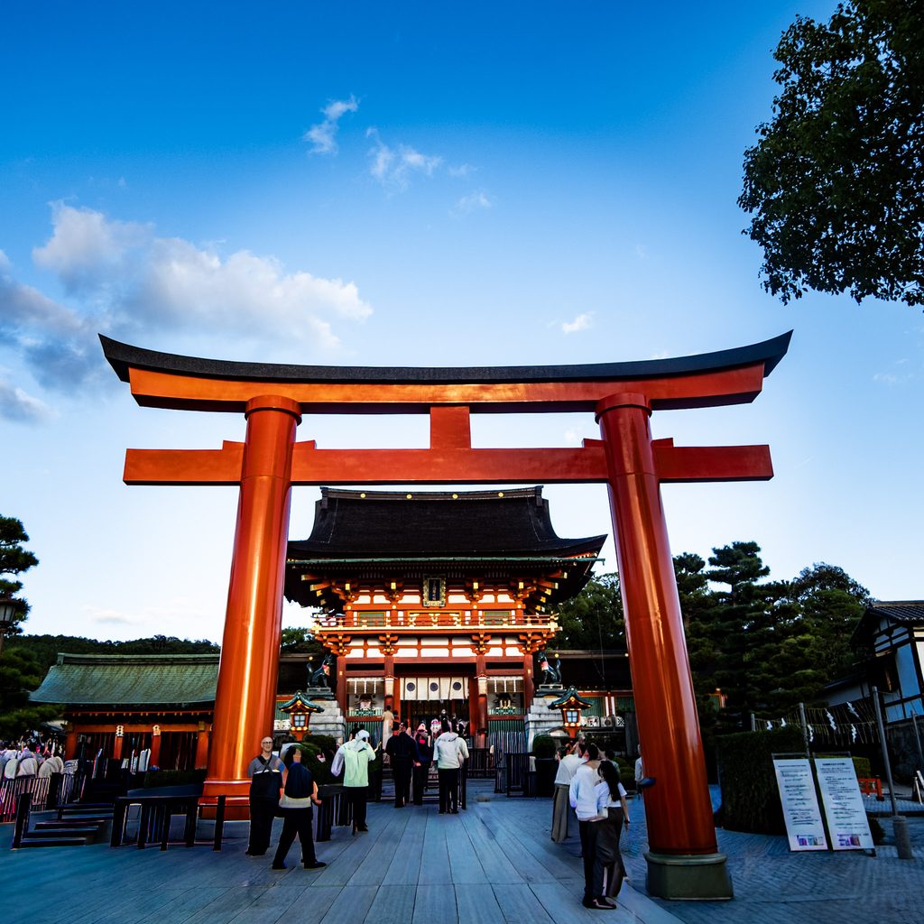 torii geant devant un temple de kyoto au coucher du soleil